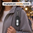 Czarny brelok przypięty do szelki plecaka, zbliżenie na plecak w drodze na zajęcia o zmierzchu, twarz poza kadrem